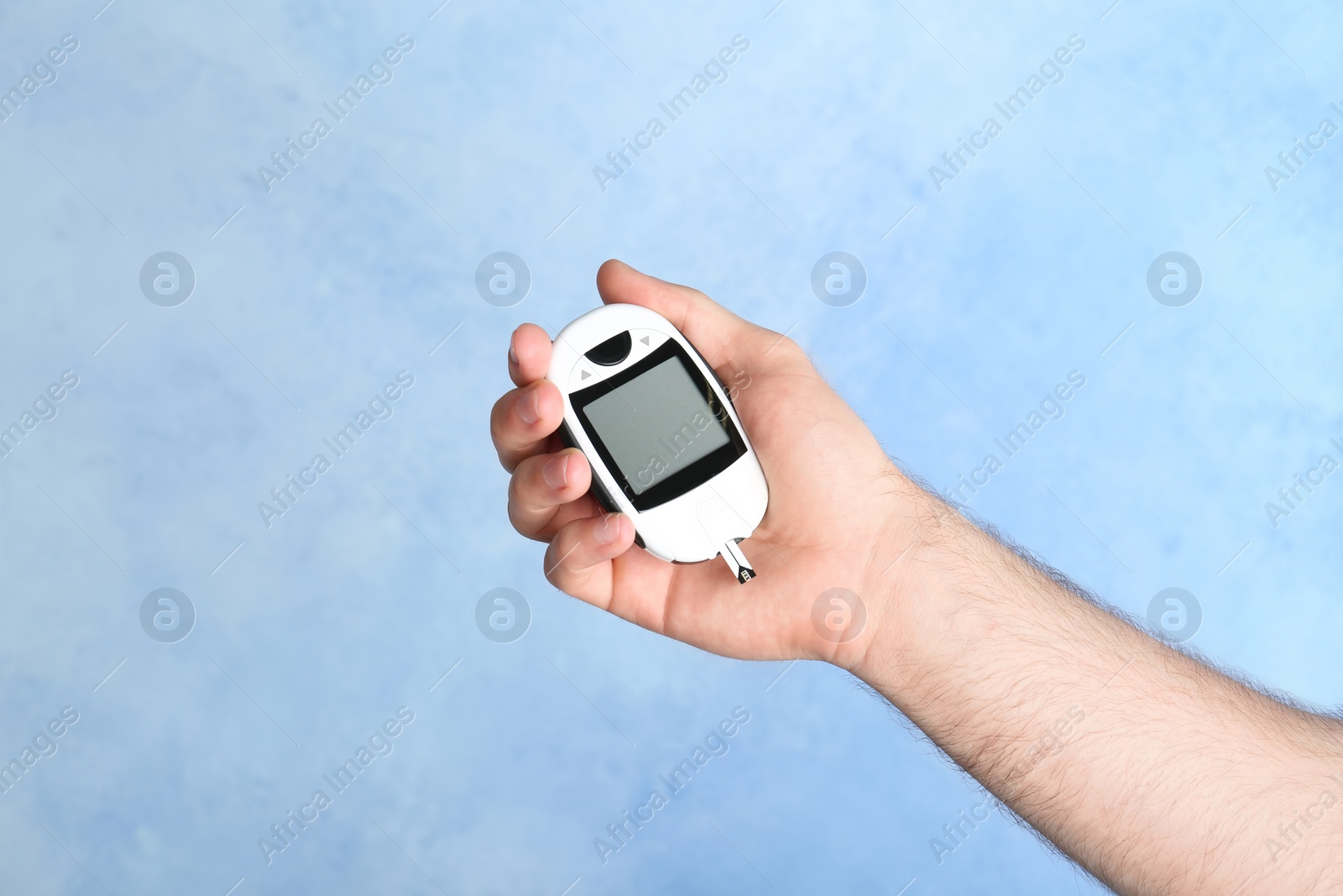 Photo of Man holding glucometer on color background. Diabetes test