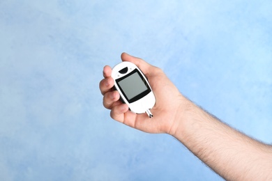 Photo of Man holding glucometer on color background. Diabetes test