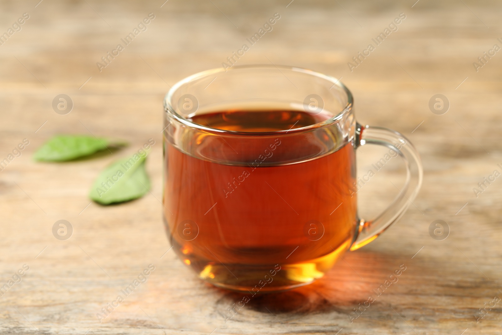 Photo of Cup of black tea on wooden table