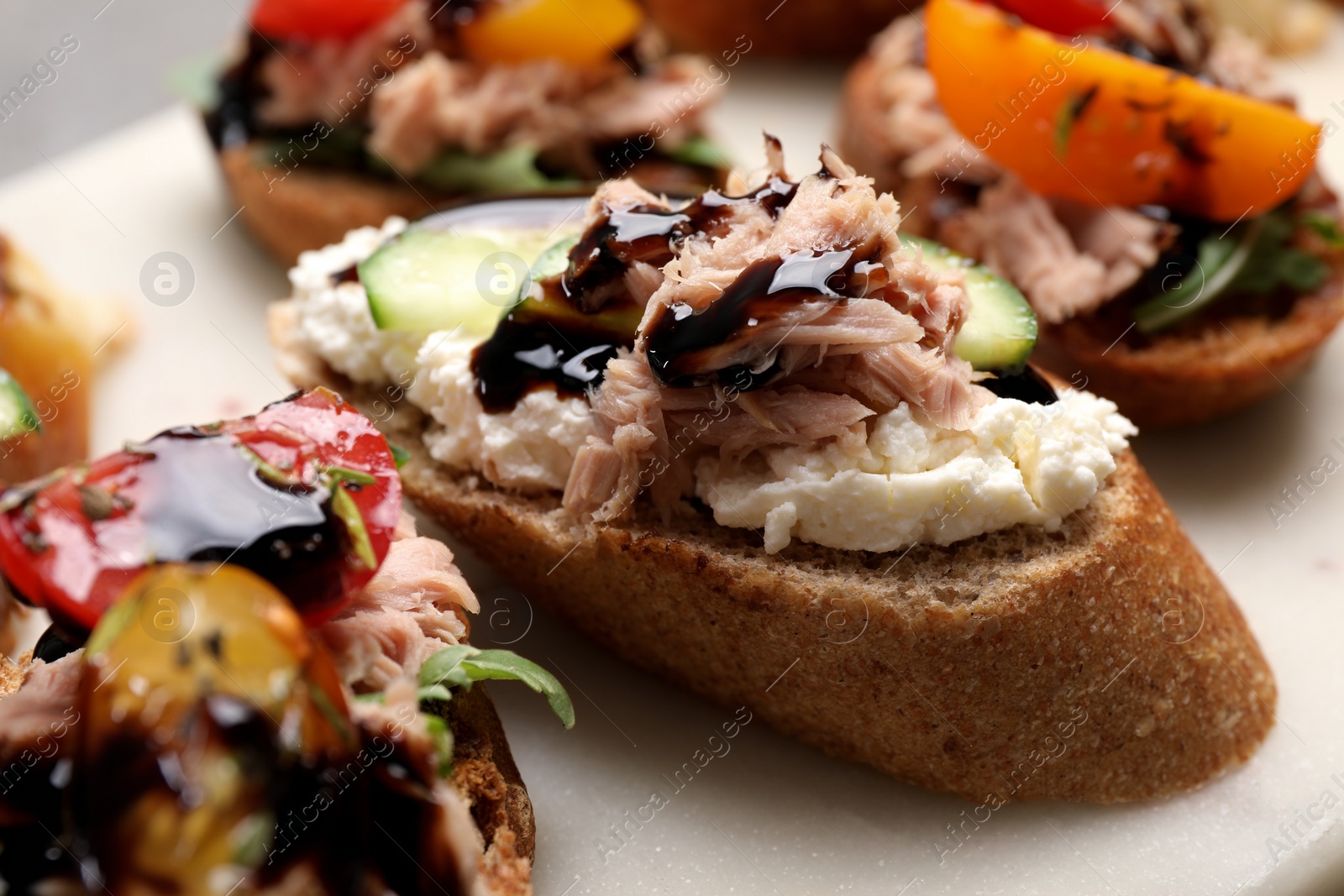 Photo of Delicious bruschettas with balsamic vinegar and different toppings on white table, closeup