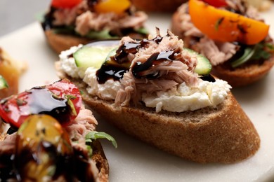Photo of Delicious bruschettas with balsamic vinegar and different toppings on white table, closeup