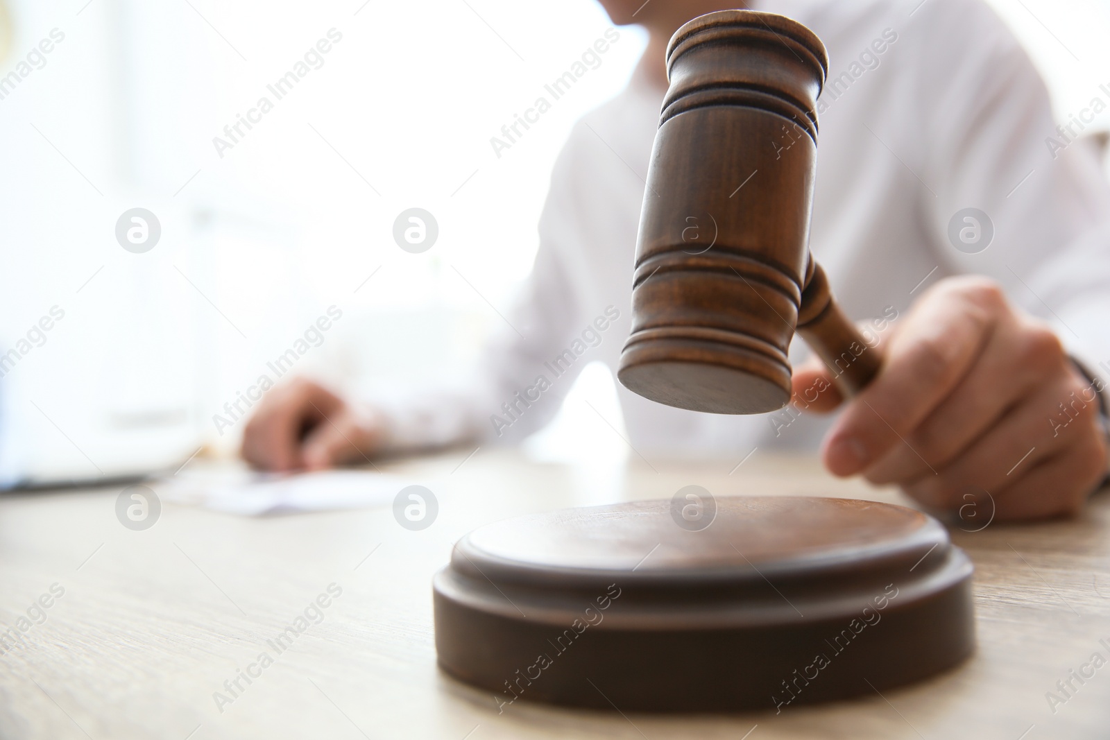 Photo of Judge with gavel at table in courtroom, closeup. Law and justice concept