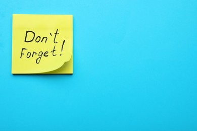 Photo of Paper note with phrase Don' t Forget on blue background, top view. Space for text