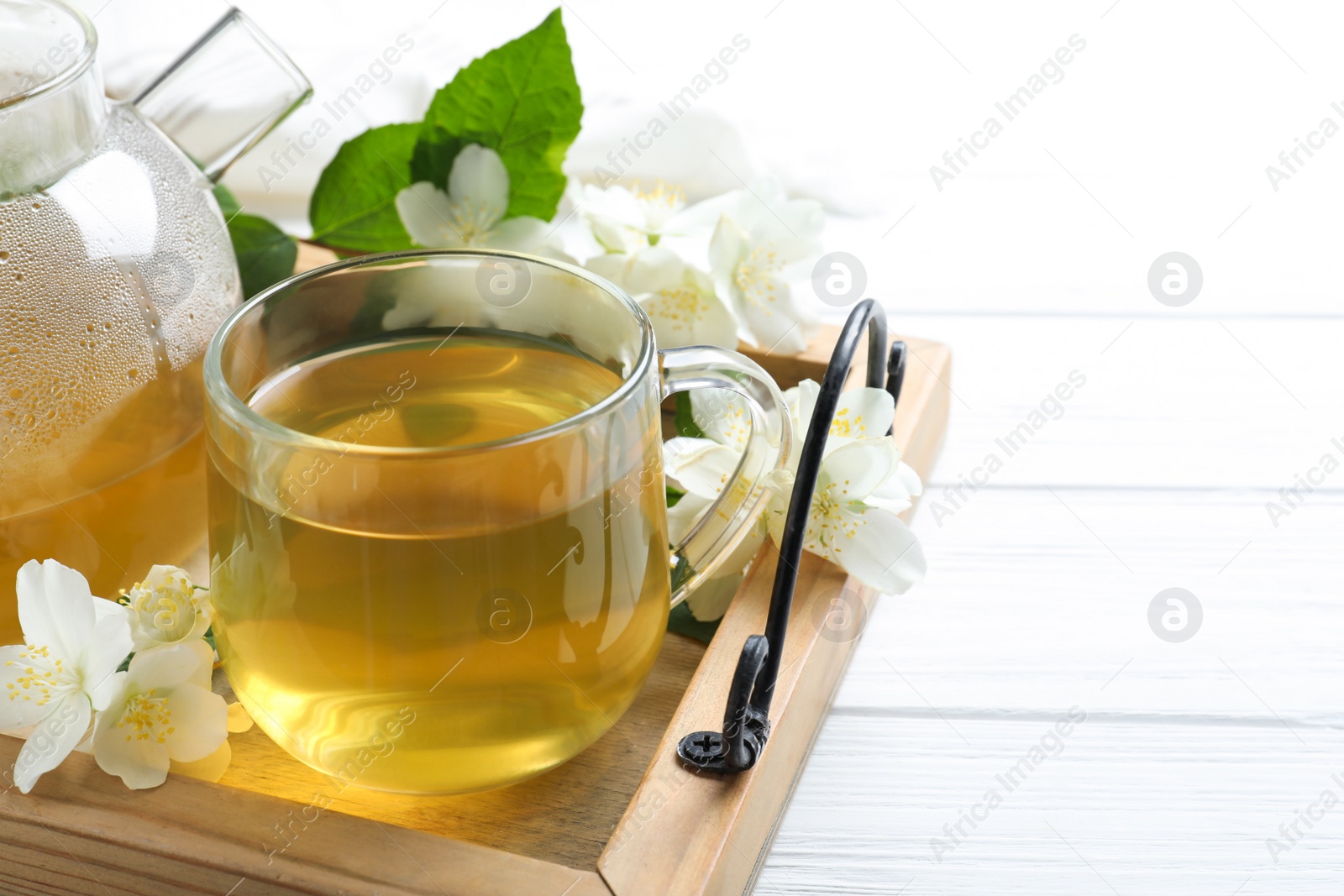 Photo of Cup of tea and fresh jasmine flowers on white wooden table