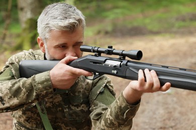 Photo of Man aiming with hunting rifle in forest