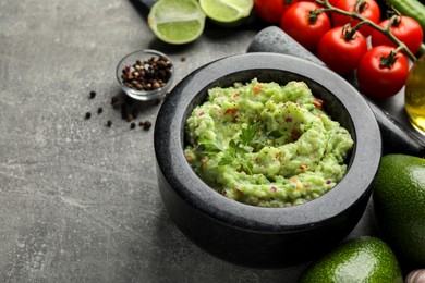 Delicious guacamole and ingredients on grey table. Space for text
