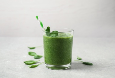 Green juice and fresh spinach leaves on light grey table