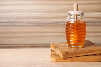 Photo of Tasty organic honey on wooden table, space for text