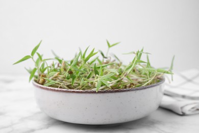 Photo of Mung bean sprouts in bowl on white marble table, closeup