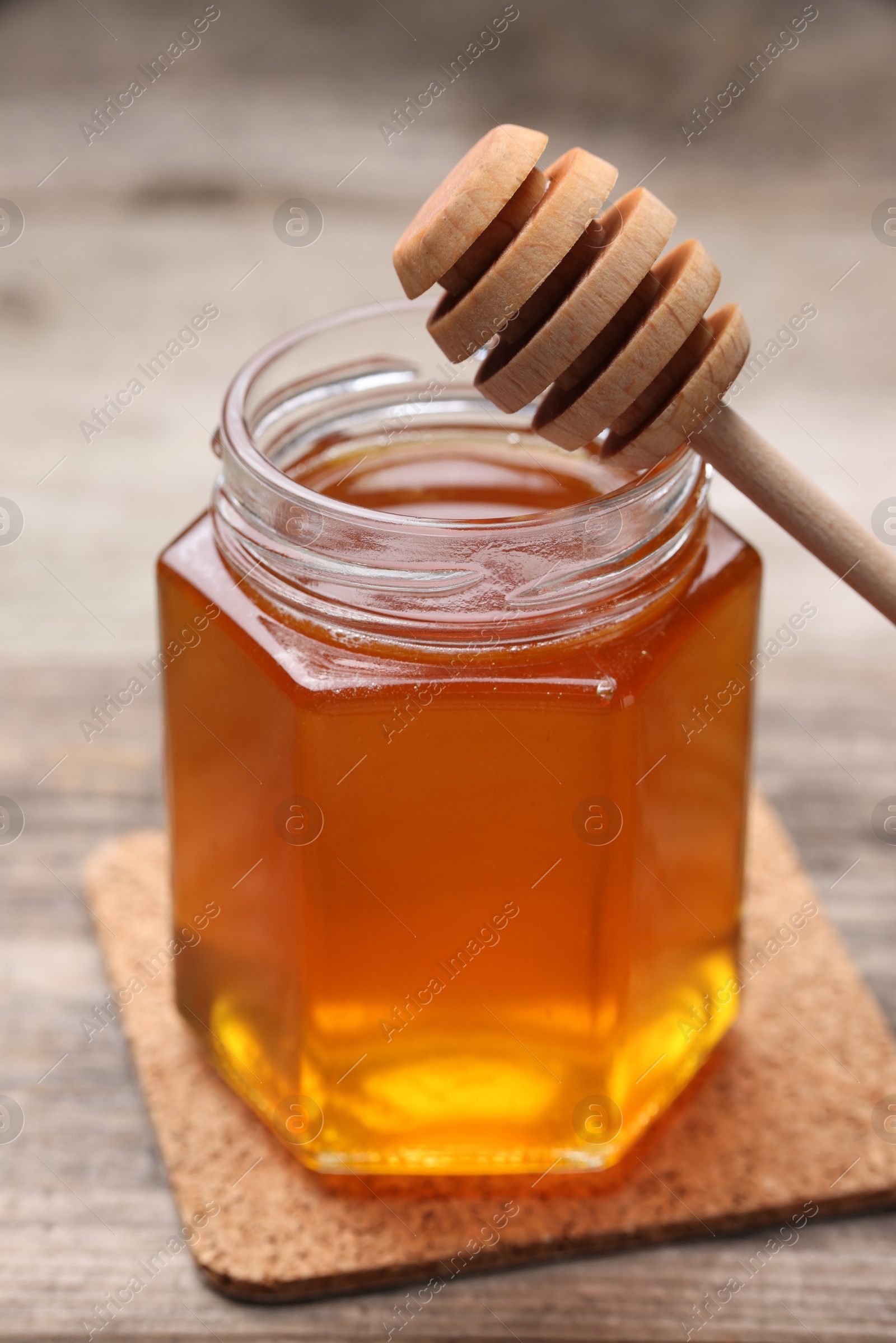 Photo of Sweet honey in jar and dipper on wooden table