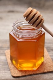 Photo of Sweet honey in jar and dipper on wooden table