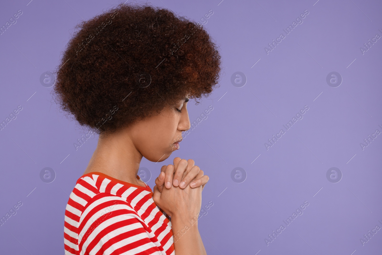 Photo of Woman with clasped hands praying to God on purple background. Space for text