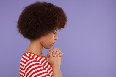 Woman with clasped hands praying to God on purple background. Space for text