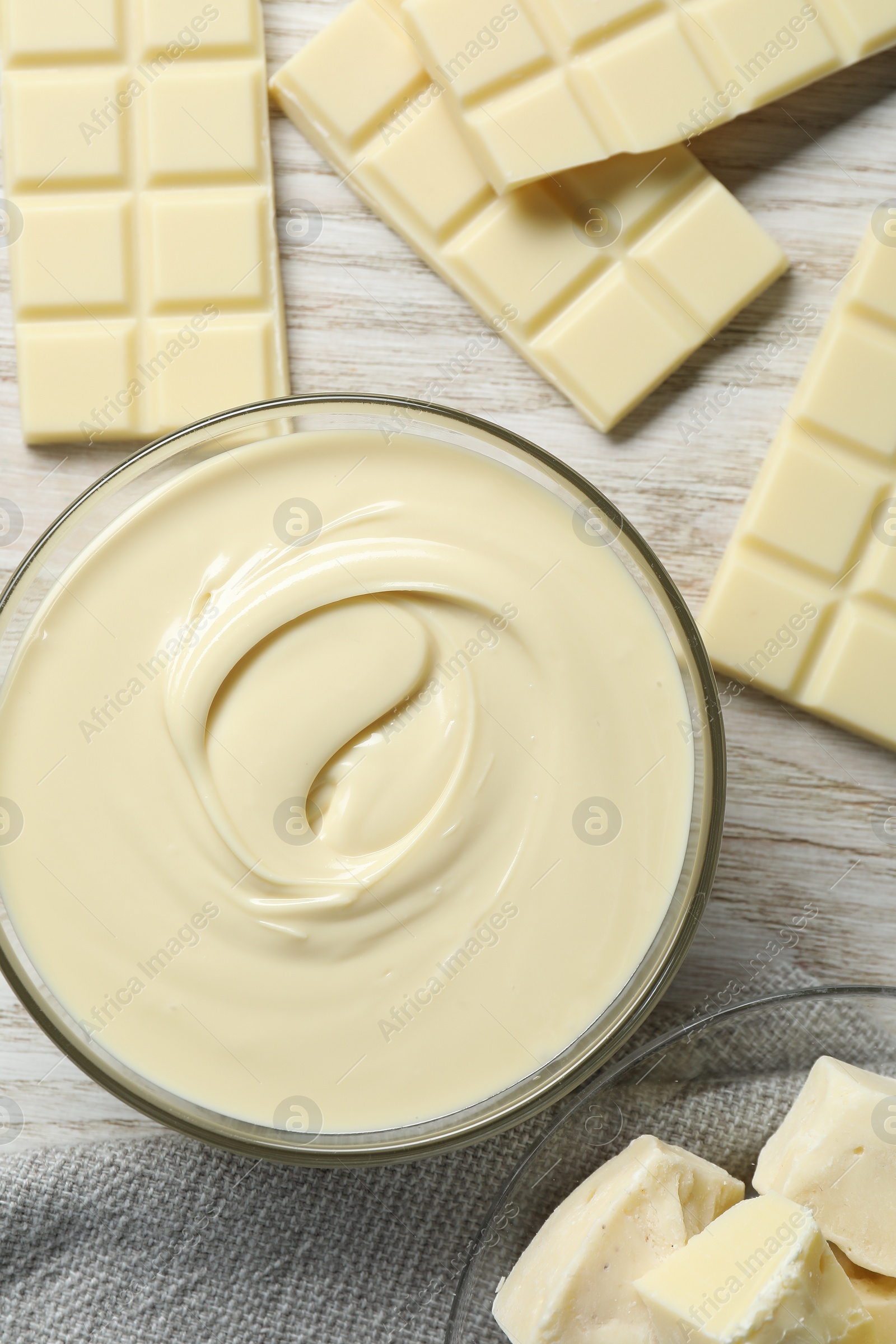 Photo of Tasty white chocolate paste in bowl and pieces on table, flat lay