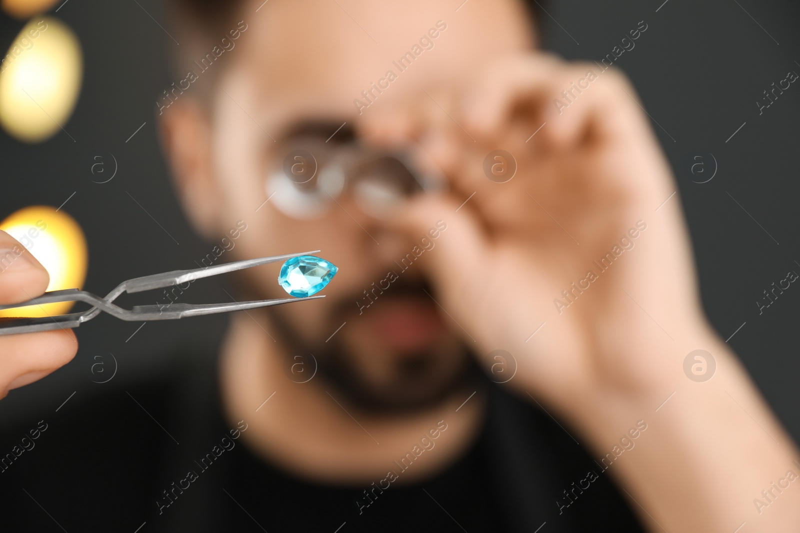 Photo of Male jeweler evaluating gemstone in workshop, closeup