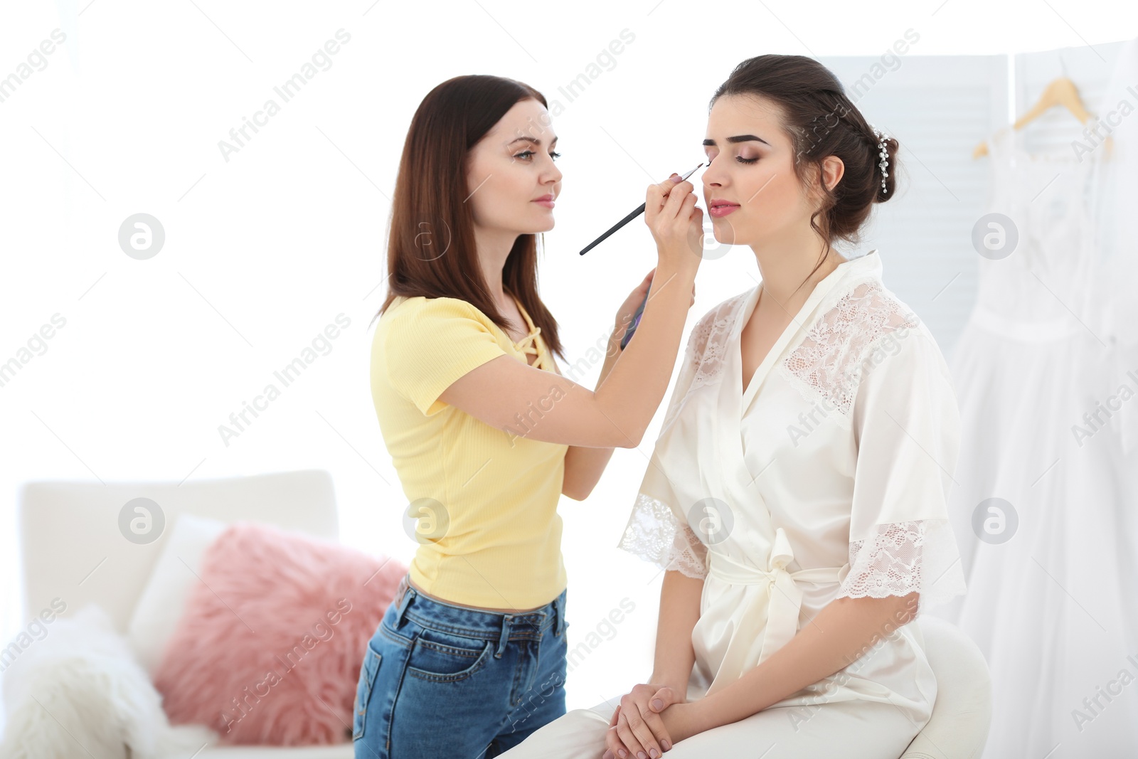 Photo of Professional makeup artist working with young bride in salon