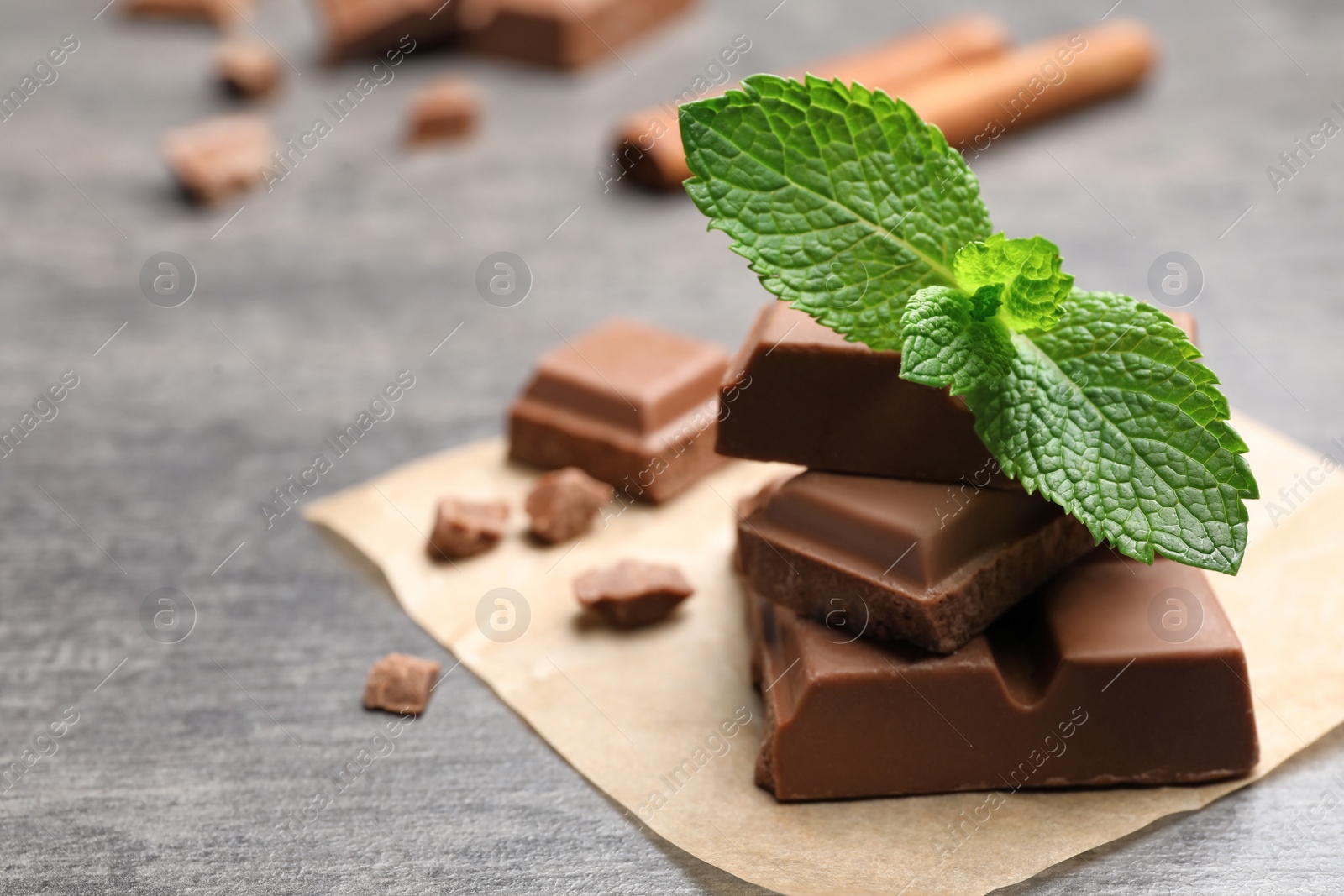 Photo of Pieces of milk chocolate with mint on gray table