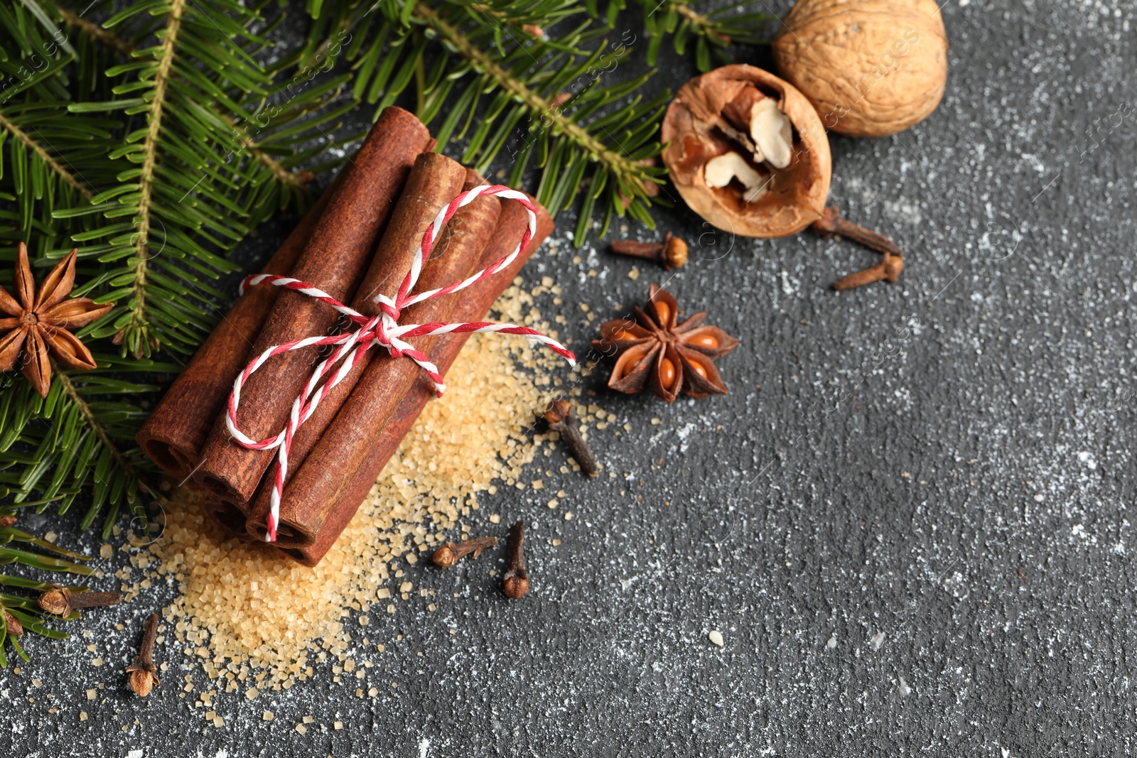 Photo of Different aromatic spices and fir branches on grey textured table, flat lay. Space for text