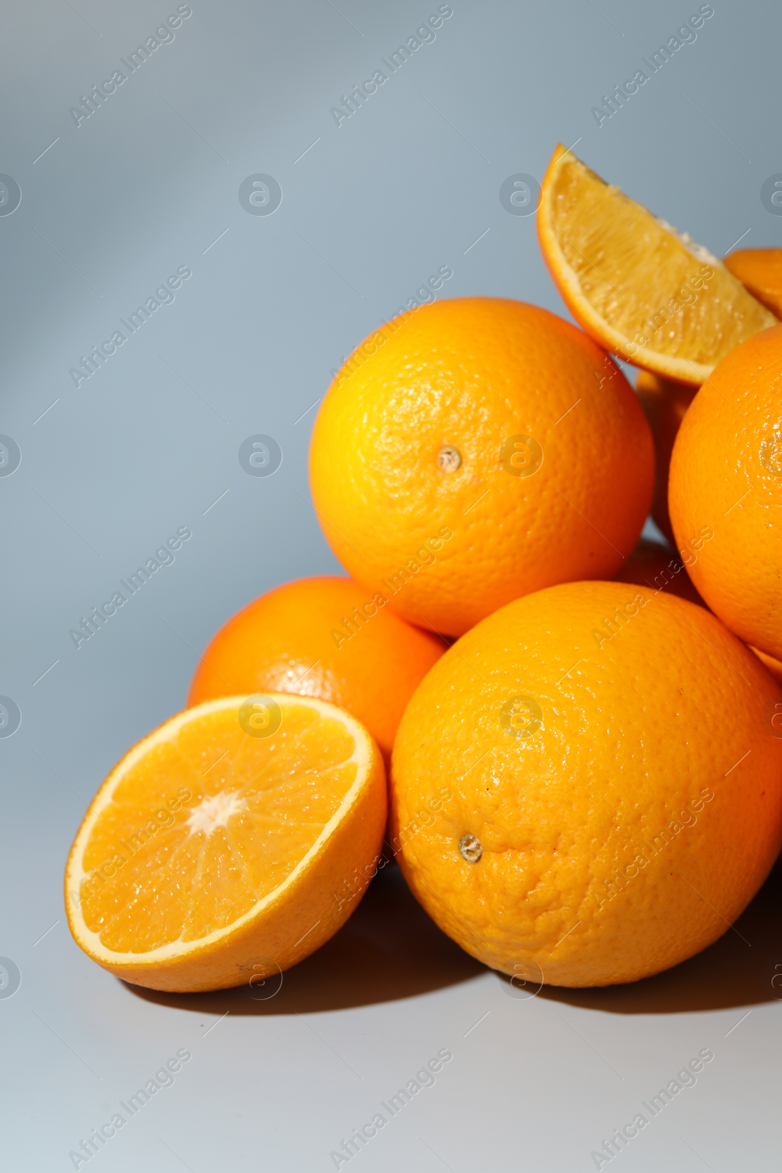 Photo of Many whole and cut oranges on grey background