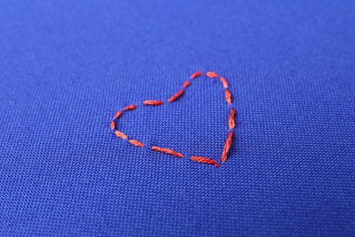 Red embroidered heart on blue cloth, closeup