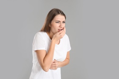 Photo of Woman suffering from nausea on grey background, space for text. Food poisoning