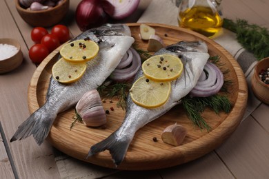 Photo of Raw dorado fish with lemon, spices and onion on table, closeup