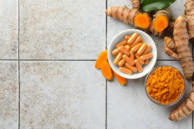 Photo of Aromatic turmeric powder, pills and raw roots on light tiled table, flat lay. Space for text