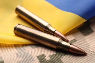 Military bullets and Ukrainian flag on pixel camouflage background, closeup