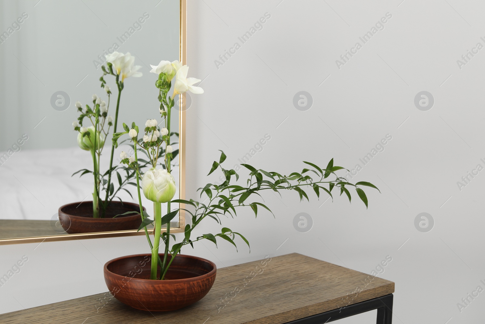 Photo of Stylish ikebana with beautiful flowers and green branch carrying cozy atmosphere at home