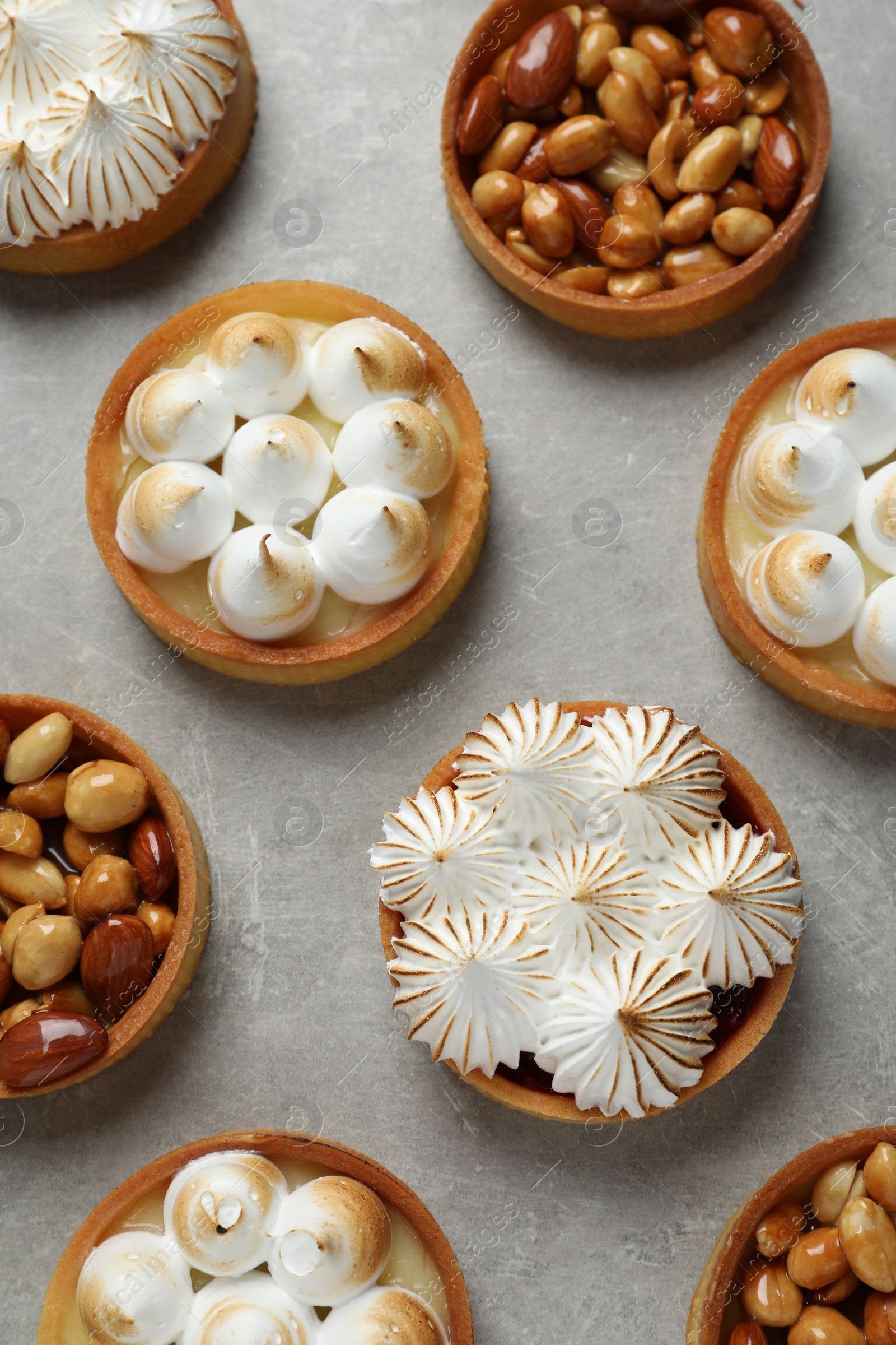 Photo of Many different tartlets on grey table, flat lay. Delicious dessert
