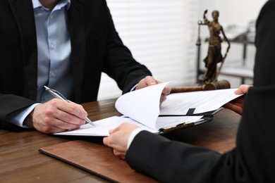 Photo of Man signing document in lawyer's office, closeup