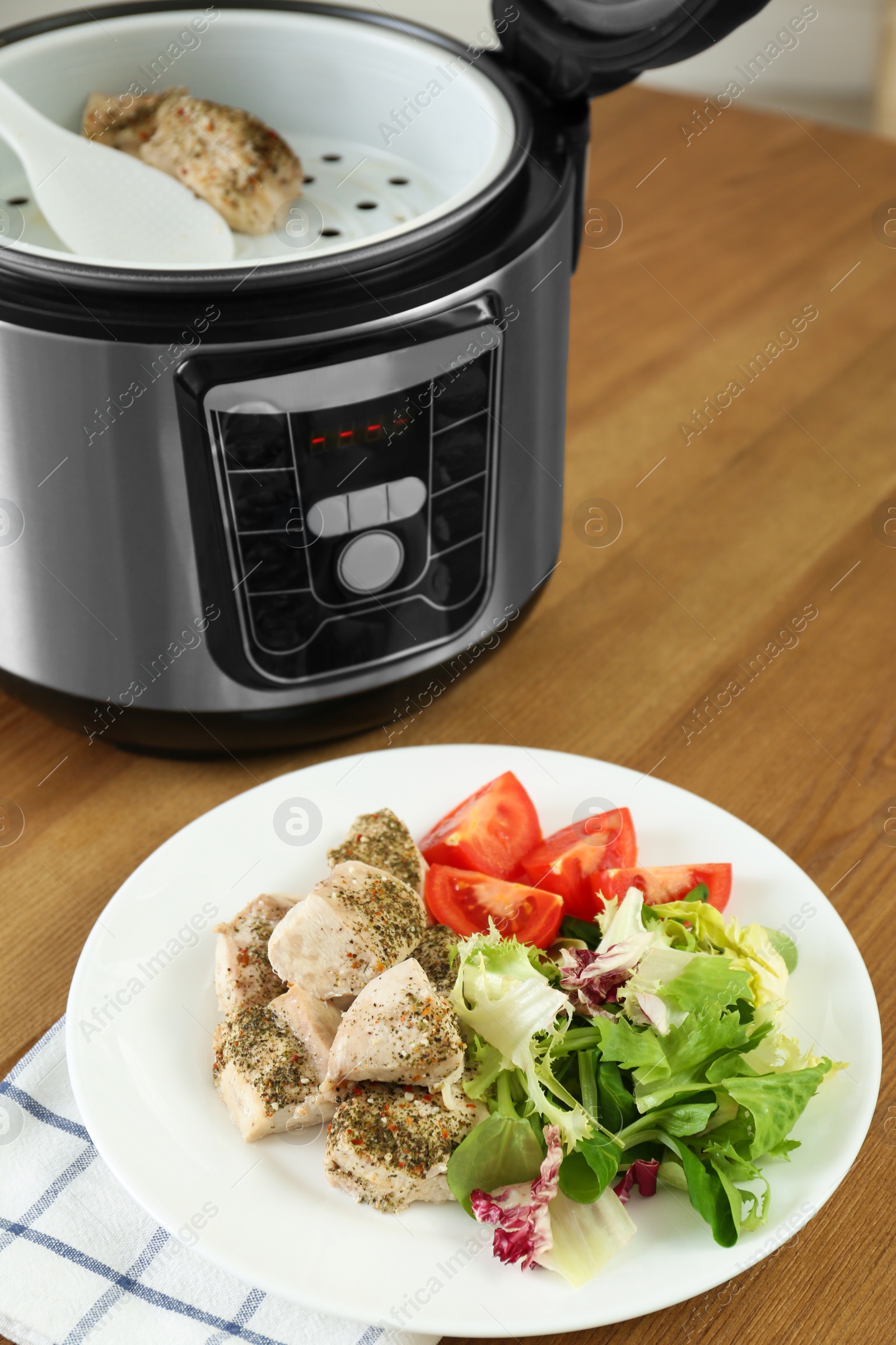 Photo of Delicious chicken with vegetables and modern multi cooker on wooden table