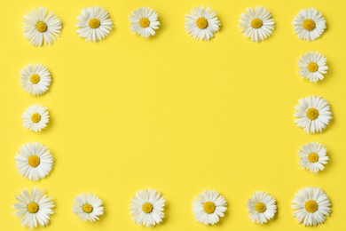 Photo of Frame of daisy flowers on yellow background, flat lay. Space for text