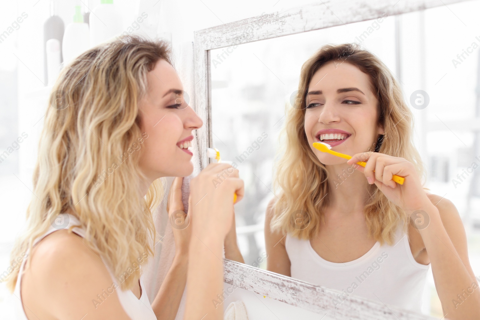 Photo of Young woman brushing her teeth in bathroom