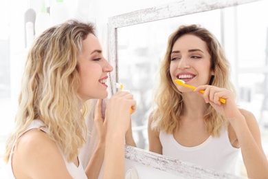 Photo of Young woman brushing her teeth in bathroom