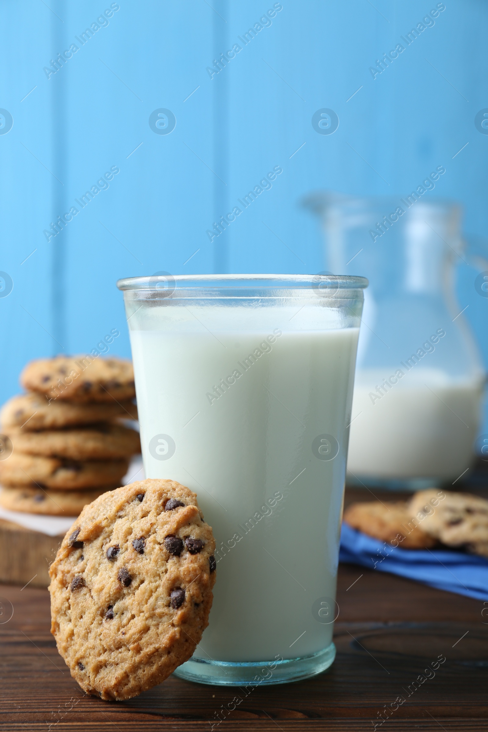 Photo of Delicious chocolate chip cookie and glass of milk on wooden table, closeup