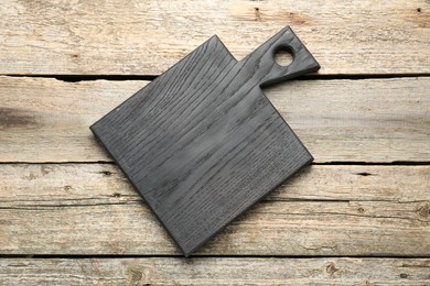 Black cutting board on old wooden table, top view
