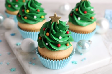 Photo of Christmas tree shaped cupcakes and decor on table, closeup