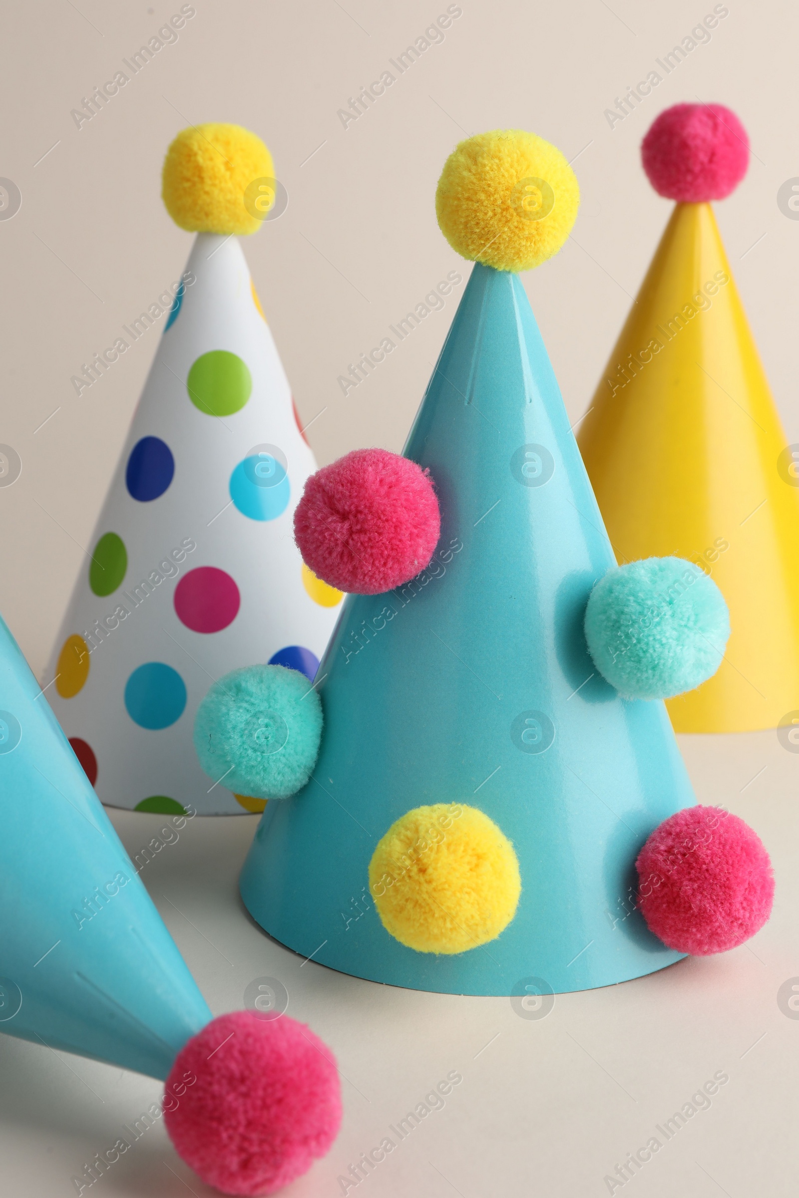 Photo of Colorful party hats with pompoms on beige background