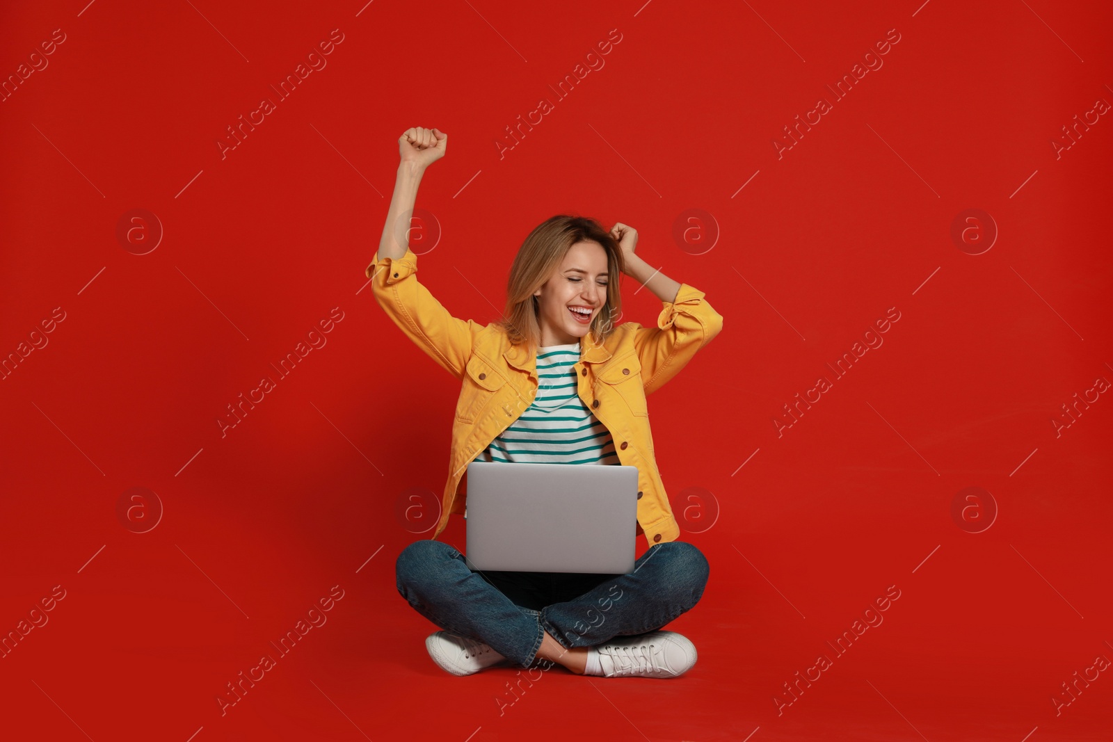 Photo of Young woman with modern laptop on red background