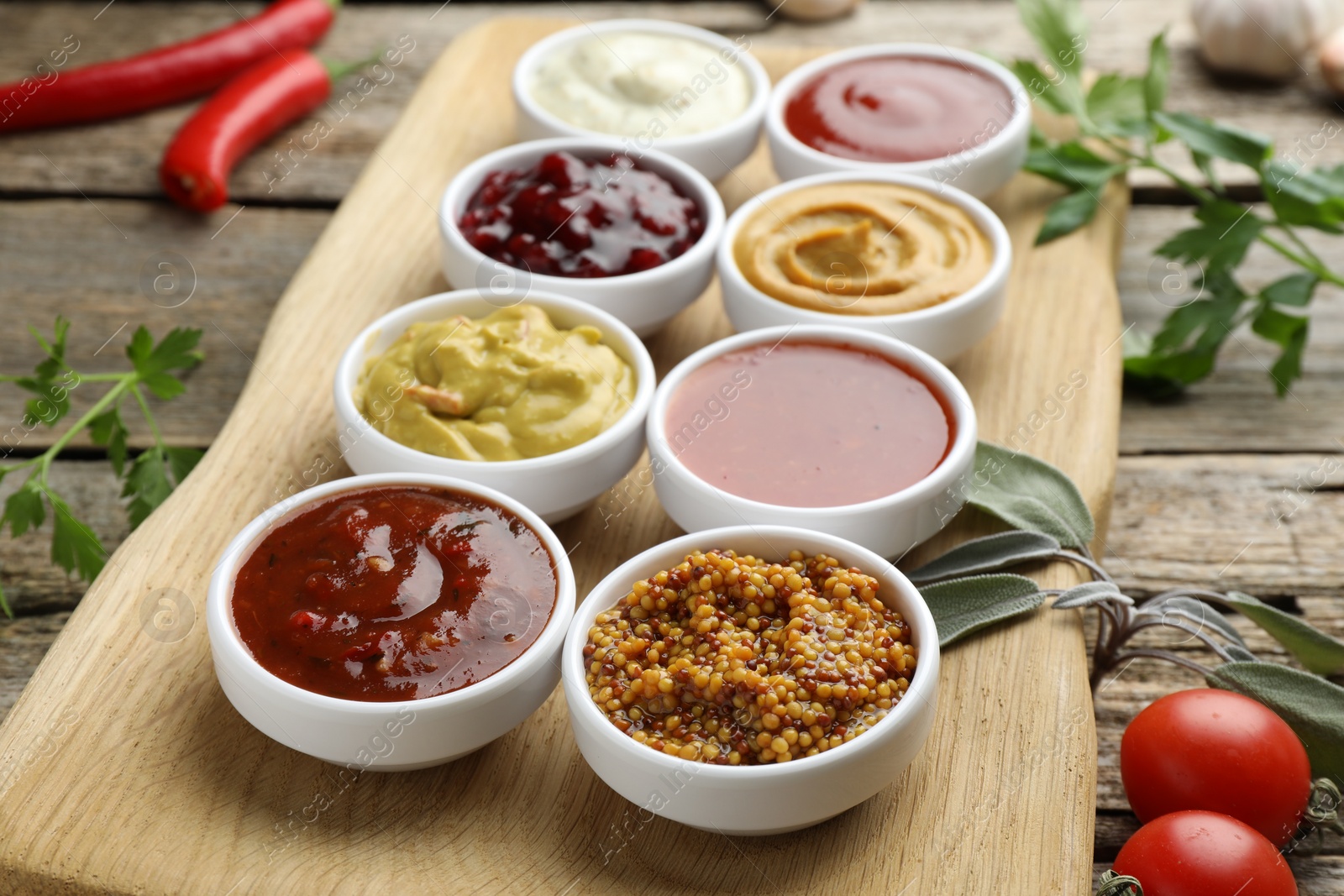 Photo of Different tasty sauces in bowls and ingredients on wooden table, closeup