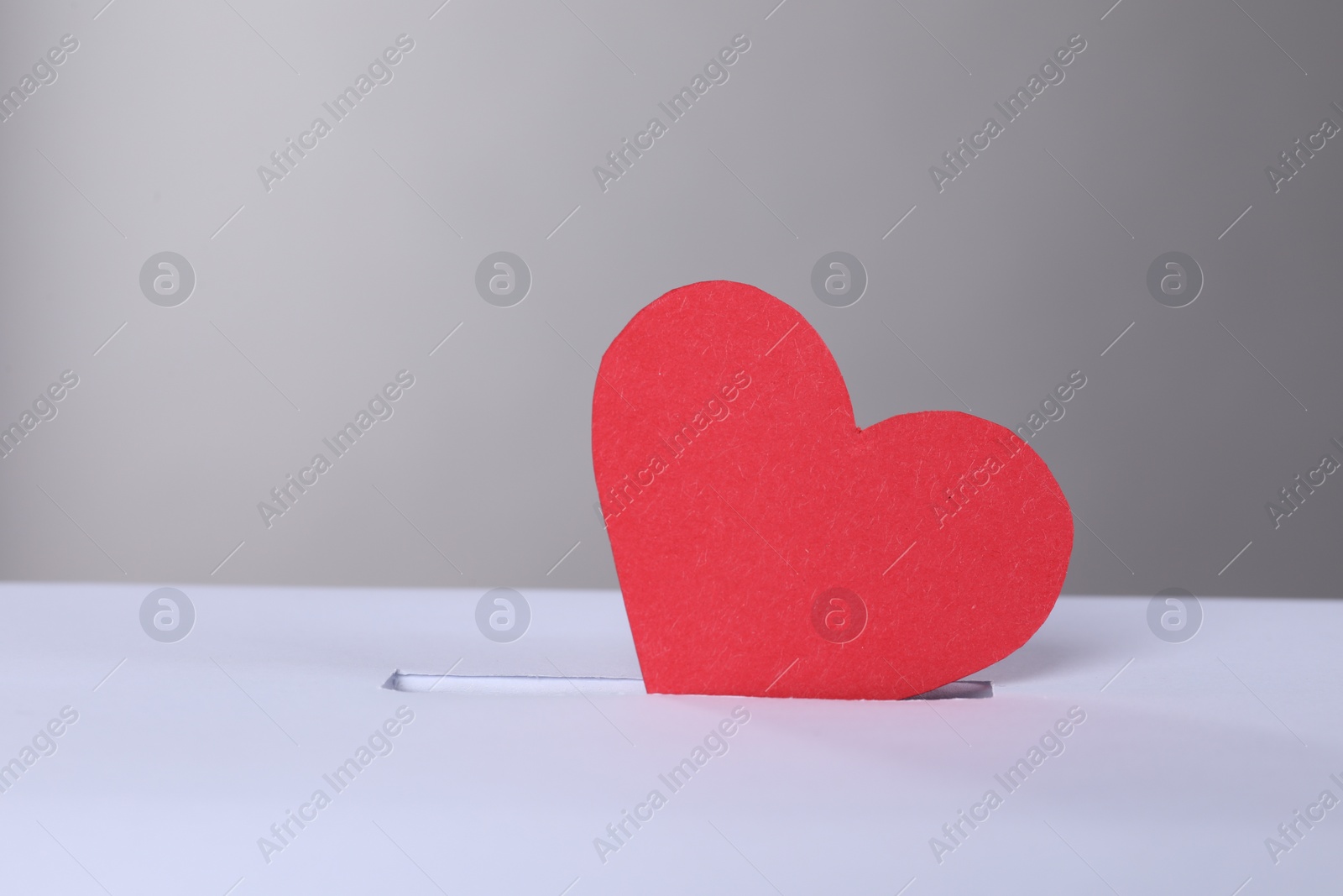 Photo of Red heart into slot of donation box against grey background, space for text