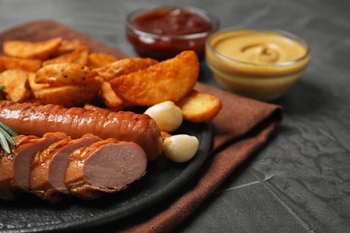 Delicious grilled sausages and vegetables on grey table, closeup. Space for text