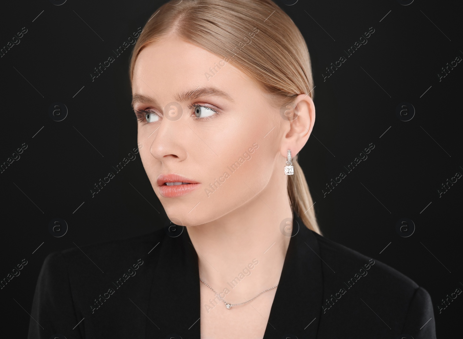 Photo of Beautiful young woman with elegant jewelry on black background