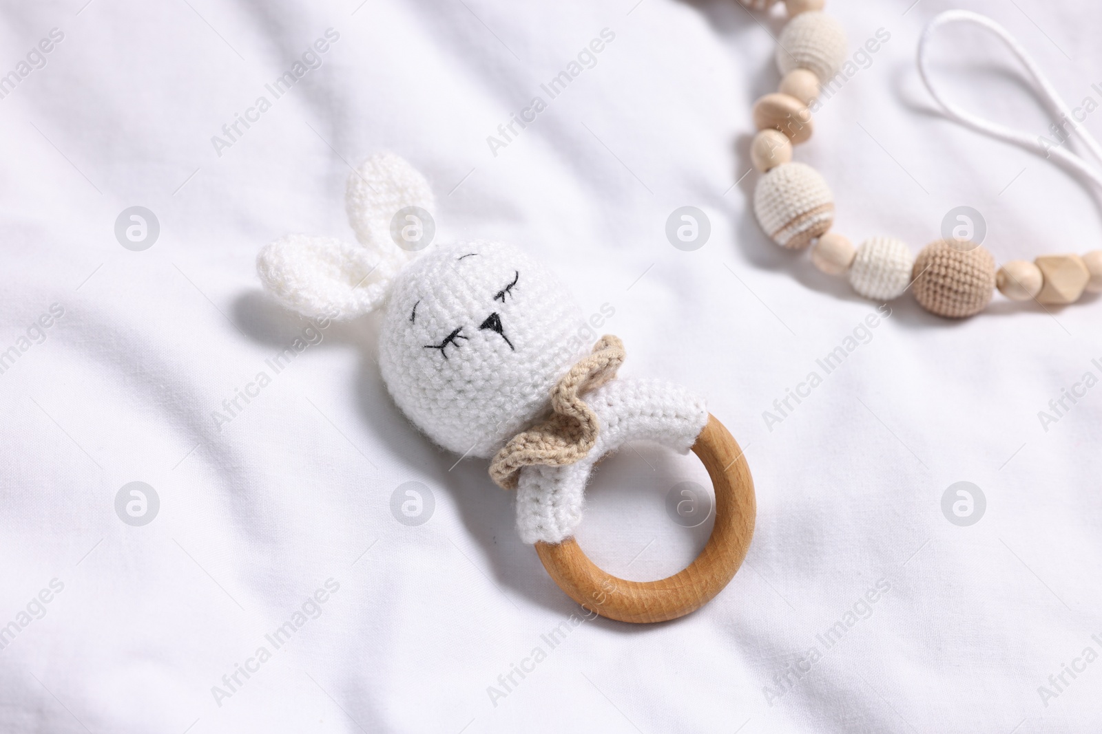 Photo of Baby accessories. Rattle and pacifier clip on white fabric