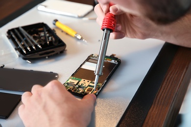 Technician repairing mobile phone at table, closeup