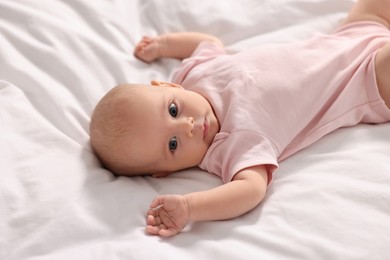 Photo of Cute little baby lying on white sheets