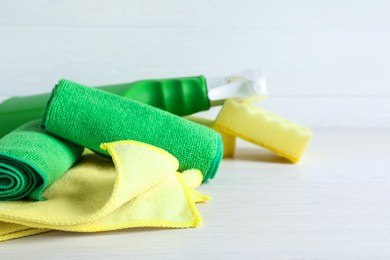 Microfiber cloths, sponges and detergent on white table, closeup. Space for text