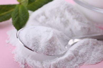 Photo of Sweet powdered fructose, spoon and mint leaves on pink background, closeup