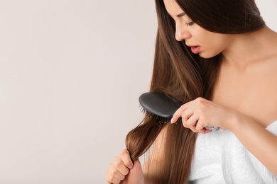 Woman struggles to brush her hair on light background. Space for text